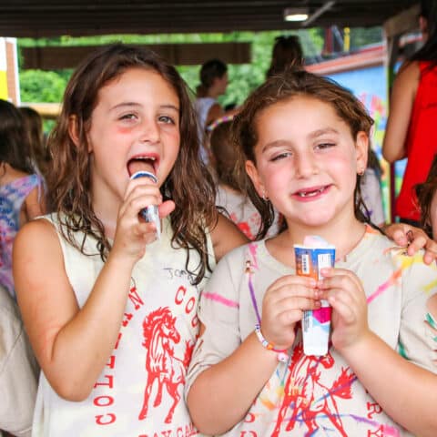 Two campers eating popsicles together.