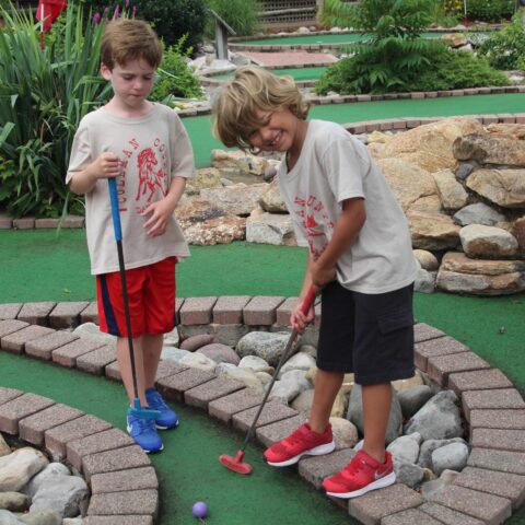 Two boy campers playing mini golf