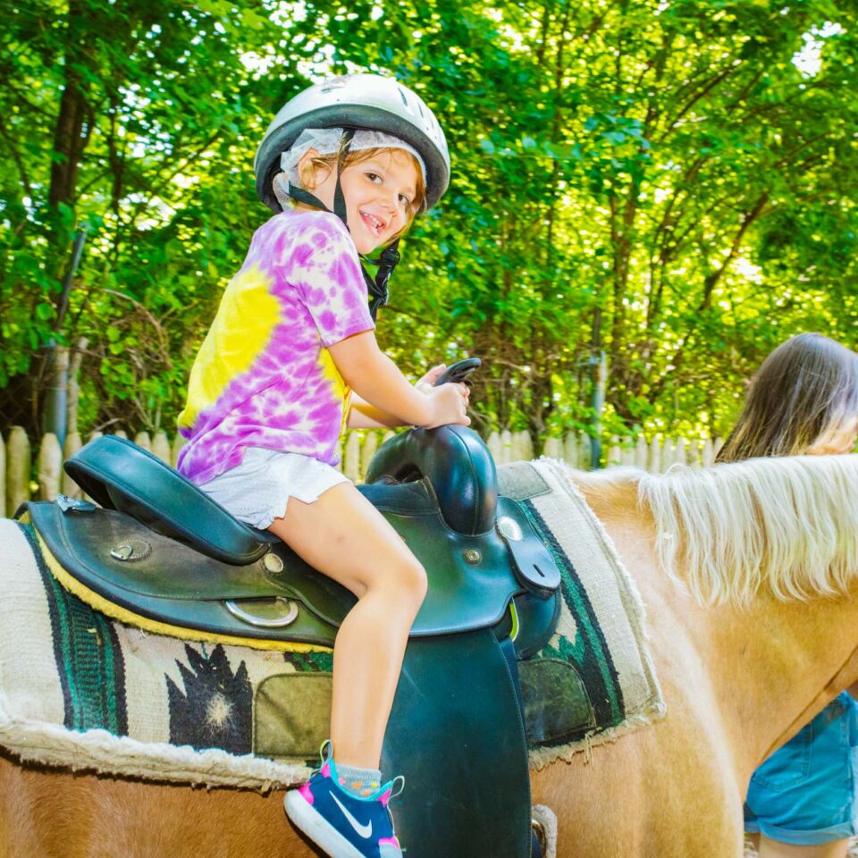 Pioneer camper sits on back of horse