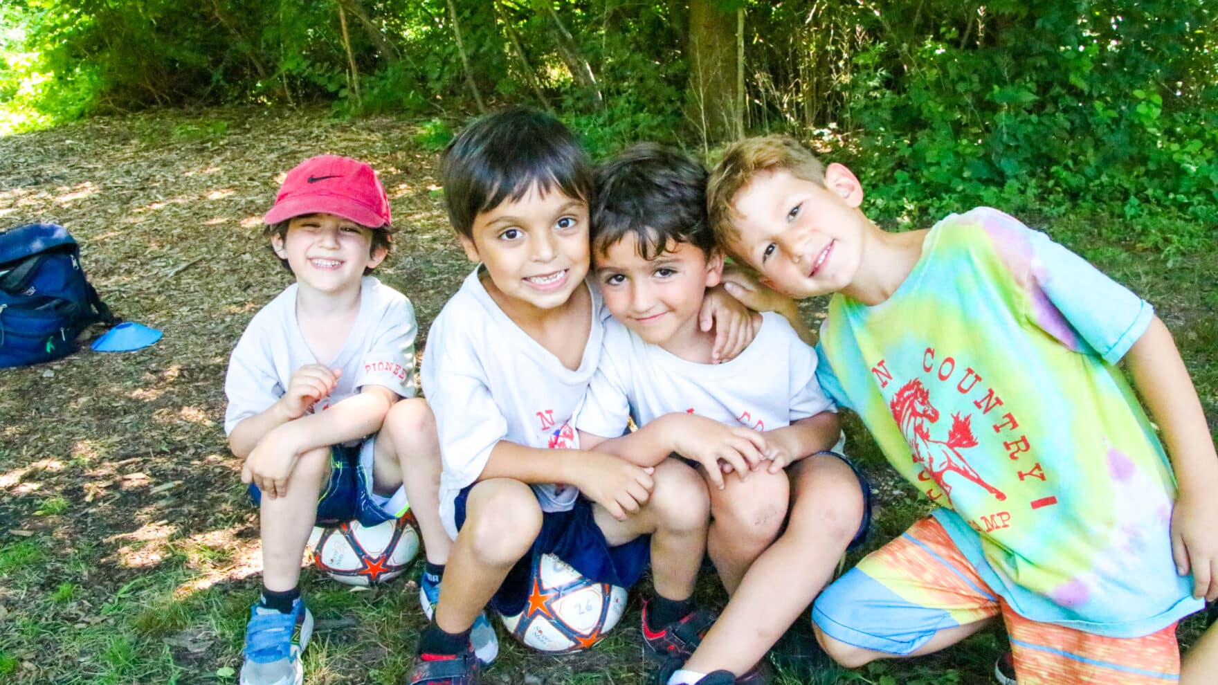 Four pioneer campers hanging out together by the woods.