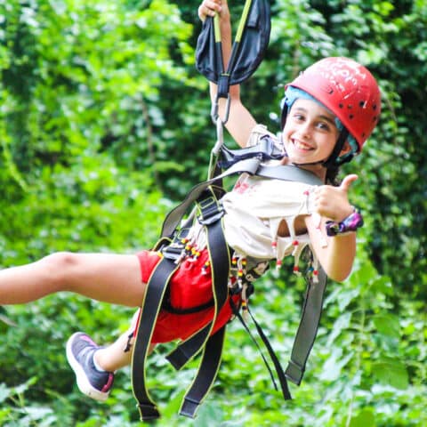 Scout camper giving a thumbs up on the zip line.