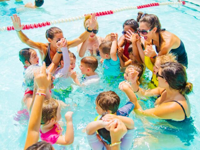 Group of young campers cheer in pool