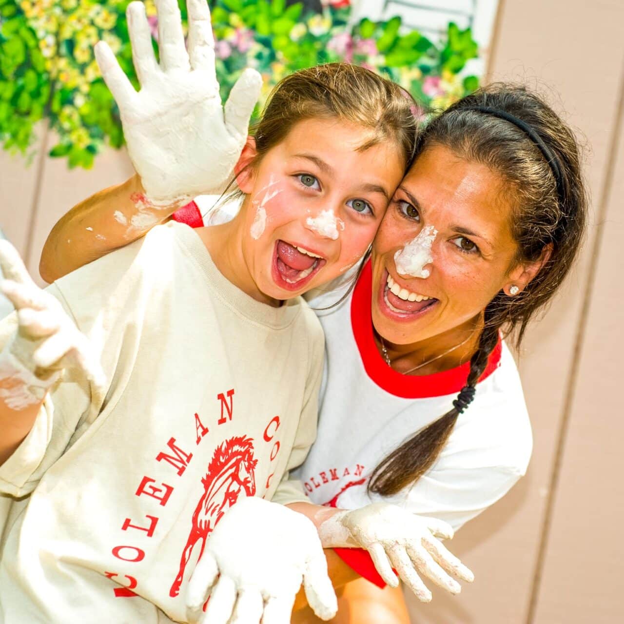 Camper and counselor with clay-covered hands