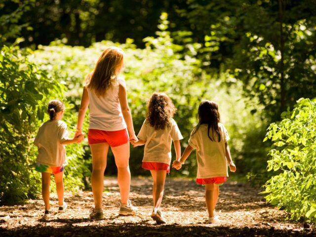 Counselor and young campers walk away from camera