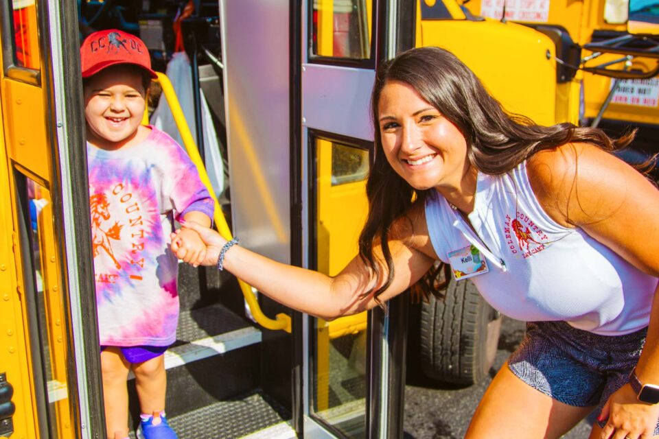 Camp director helps camper off bus