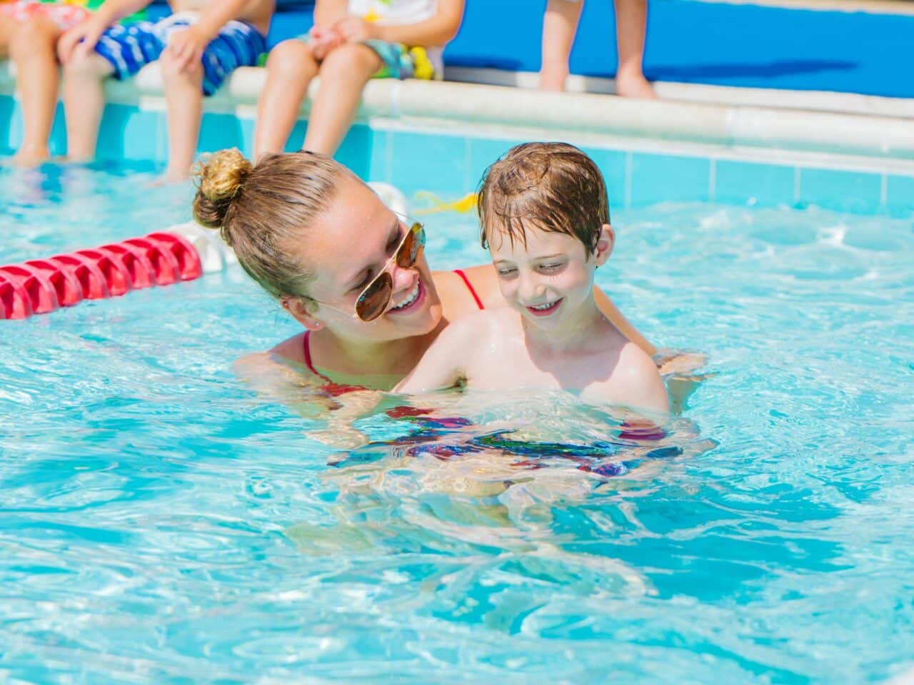 Smiling swim instructor teaches young camper