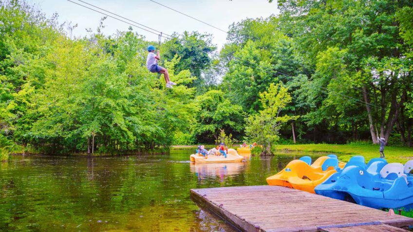 Camper ziplines over pond