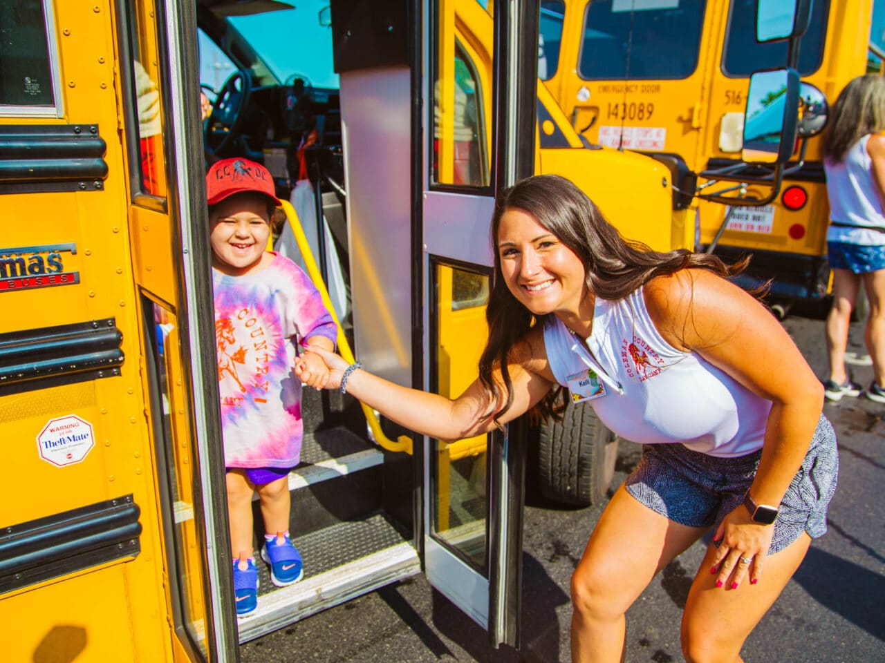 Counselor helping a camper off of the bus.