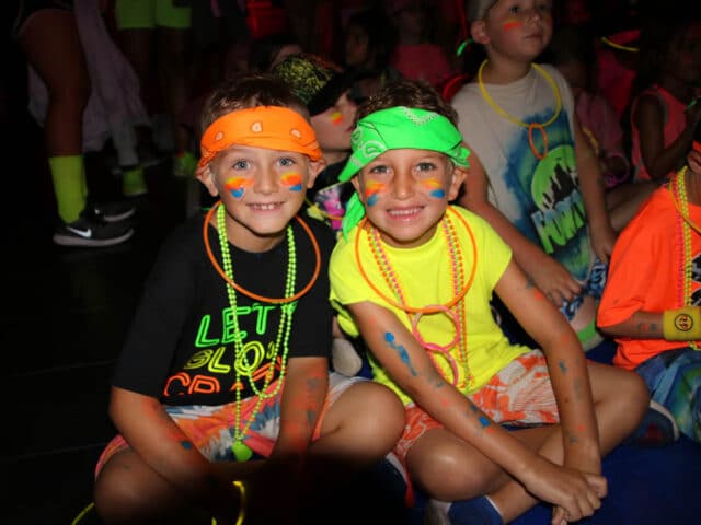 Two campers wearing glow stick necklaces and neon.