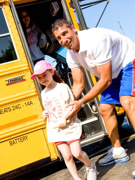 Counselor helping a child off of the bus.